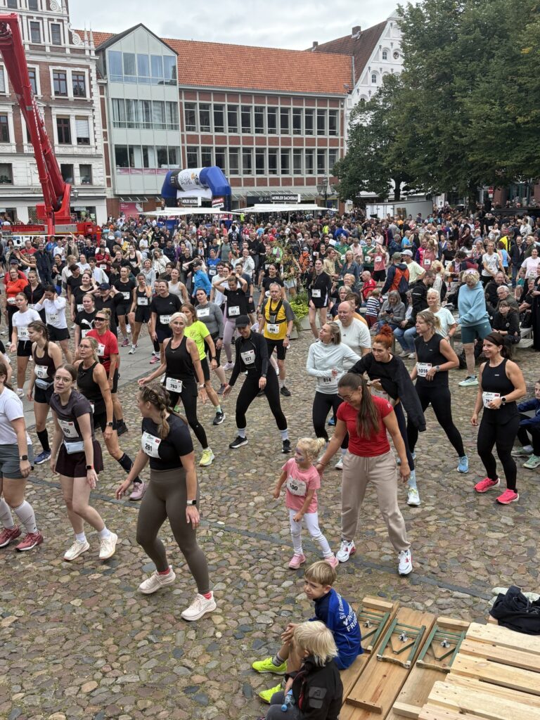 Gemeinsames Aufwärmen auf dem Marktplatz, im Hintergrund Kran und Startbogen