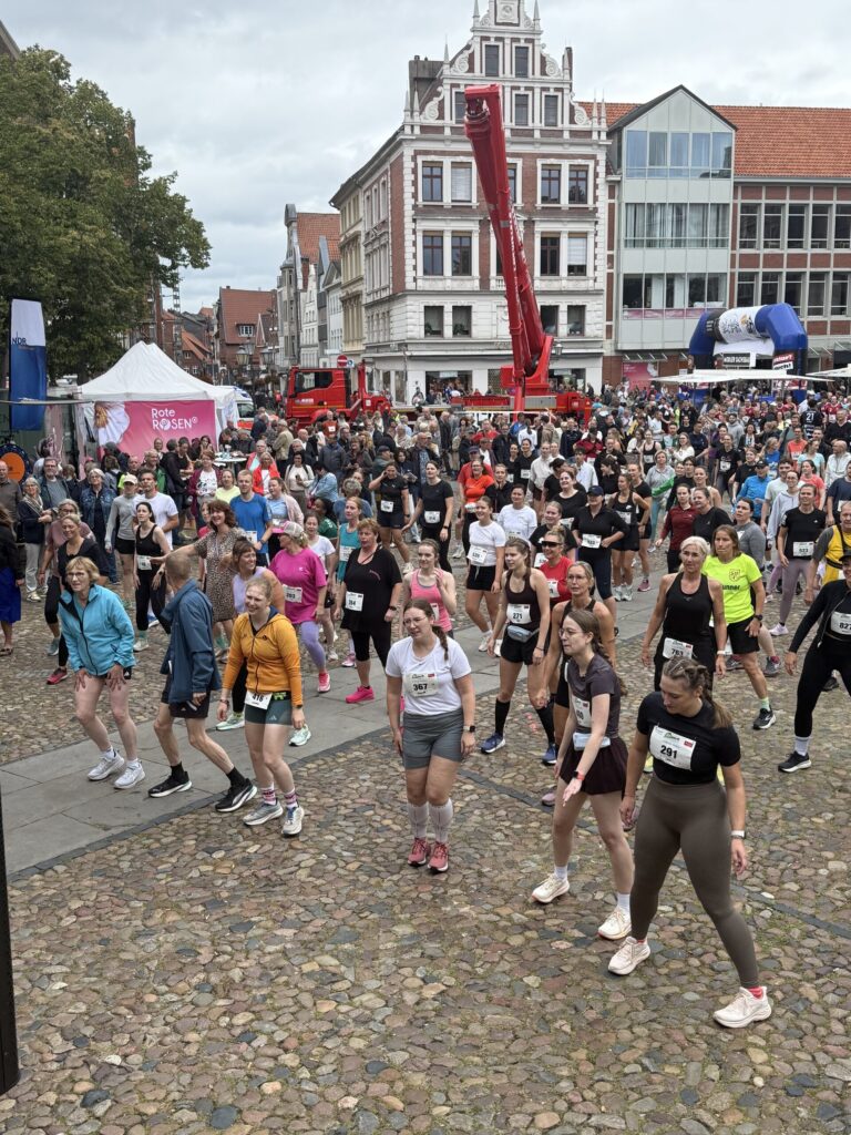 Läufer:innen beim Aufwärmen, hinten der rote Kran und der Startbogen