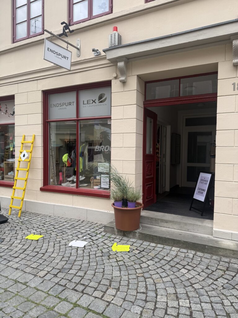 Die Startnummernausgabe beim Laufladen Endspurt: gelbe Pfeile auf dem Pflaster weisen den Weg